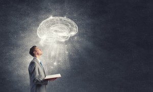 Shocked businessman holding opened book with brain picture